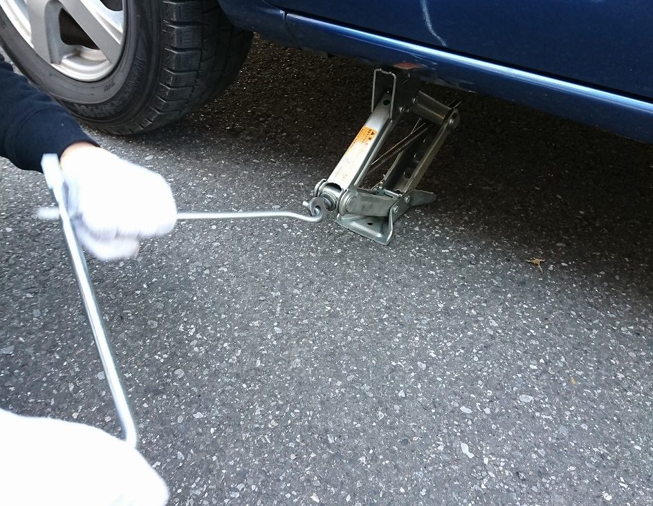 パンタジャッキのねじを回して車を持ち上げる